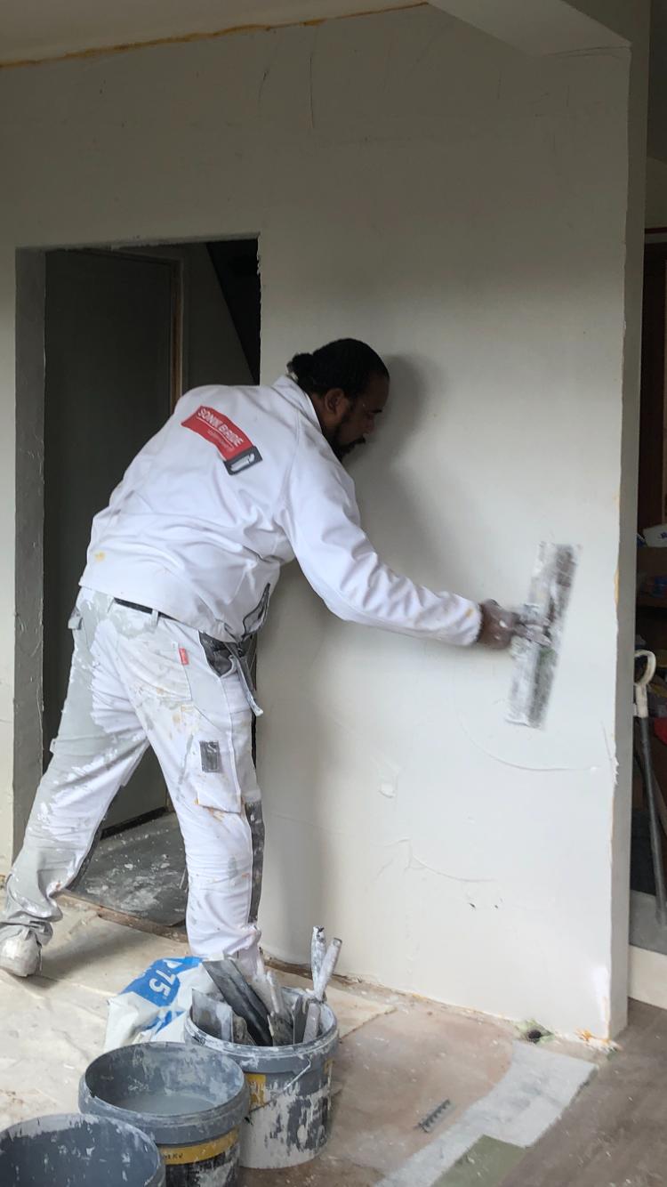 Sonny stuct een wand naast een deuropening, met emmers en zakken op de voorgrond